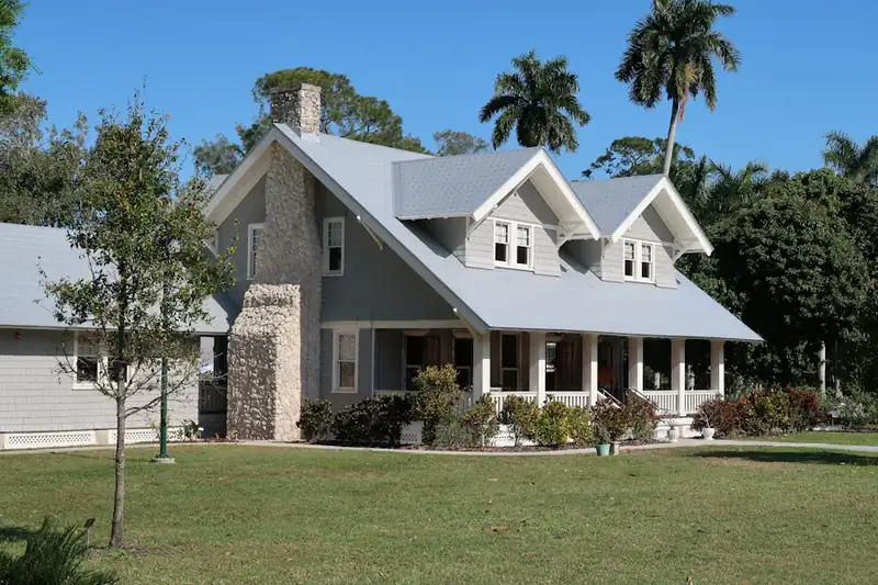 Grey house with a stone chimney and porch