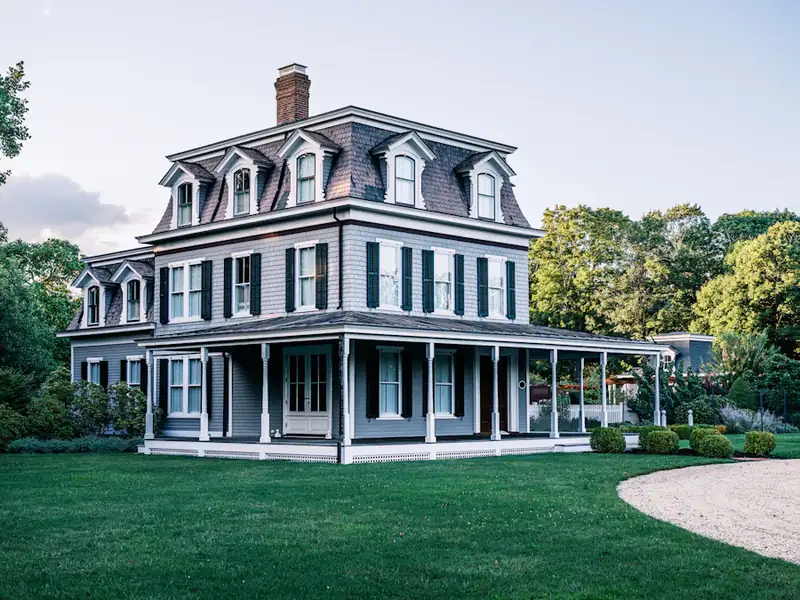 Large grey Victorian home with wraparound porch